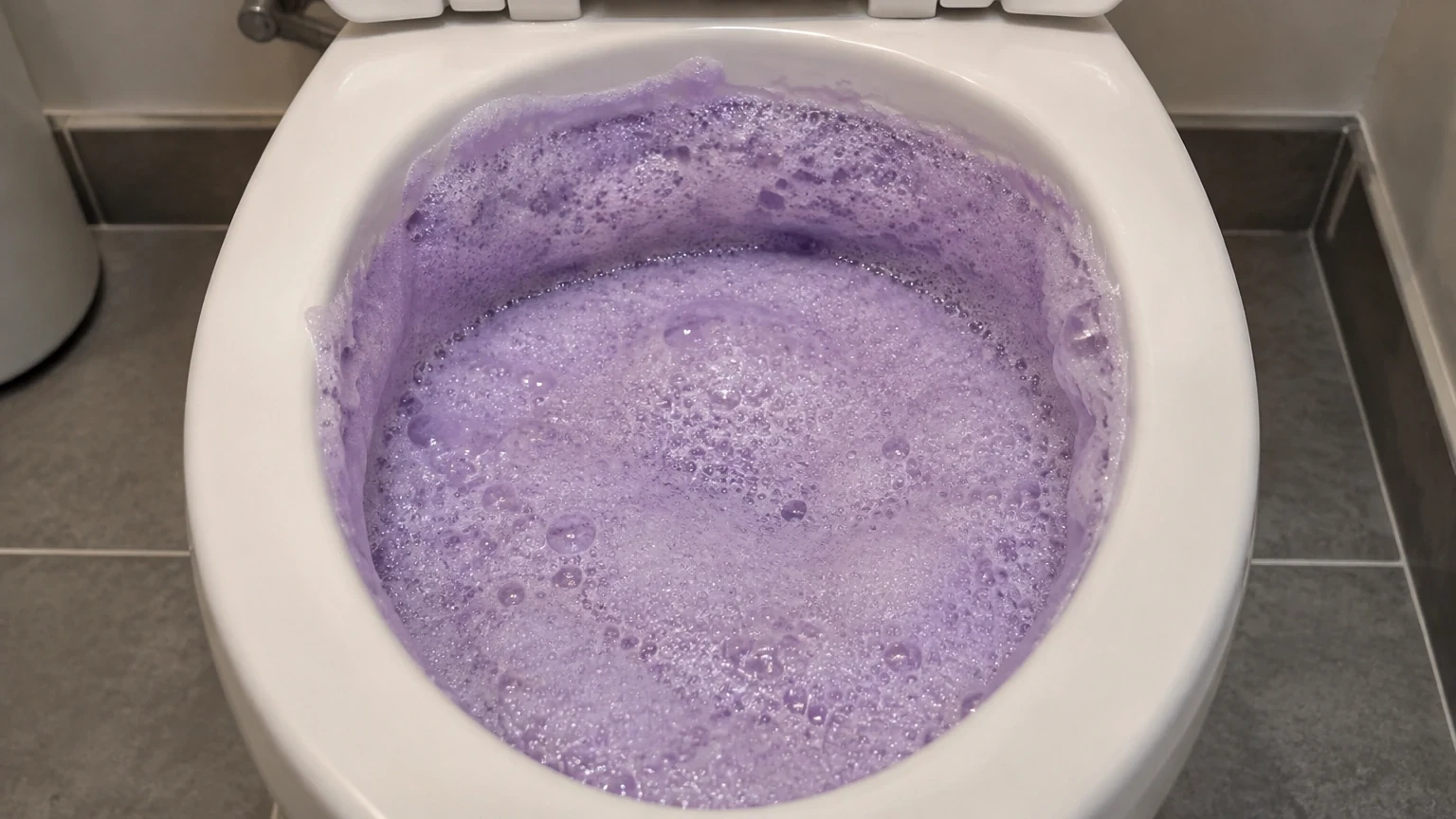 Thick lavender-purple foam filling a toilet bowl and clinging right up under the rim